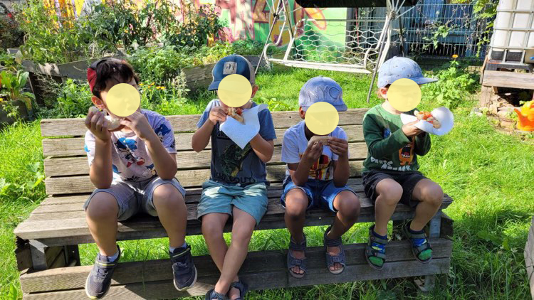 Kinder sitzen im Garten und essen